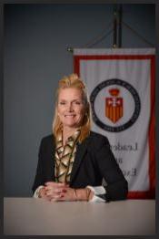 Kathleen Hunsicker sitting in front of school banner